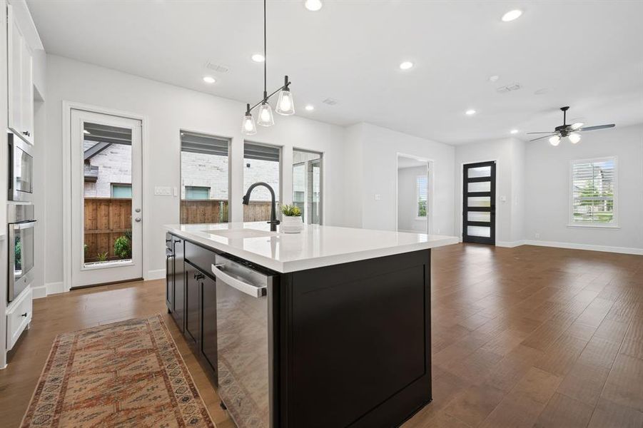 Open-concept kitchen featuring a large island with a white quartz countertops, matte black faucet, and stainless steel appliances