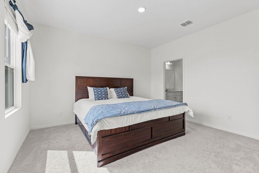 Bedroom featuring light colored carpet and ensuite bathroom Bedroom featuring light colored carpet and ensuite bathroom