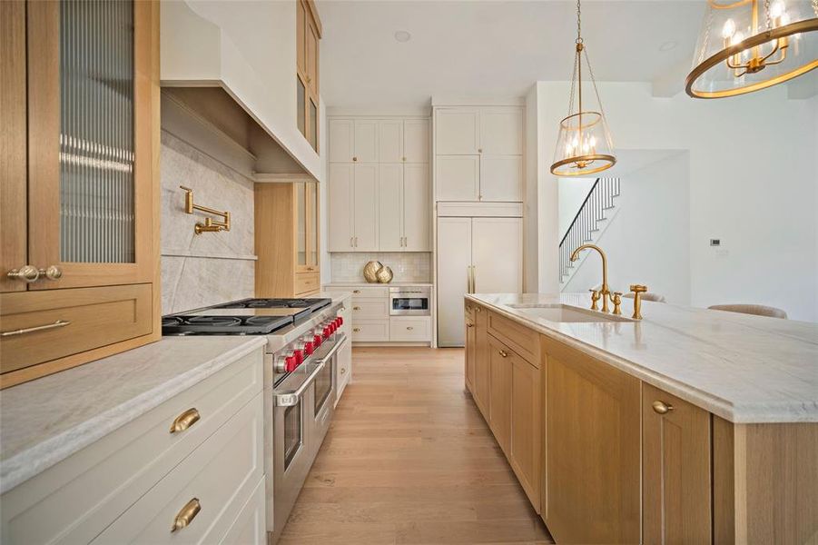 Kitchen featuring high end appliances, a chandelier, decorative backsplash, and light wood finished floors