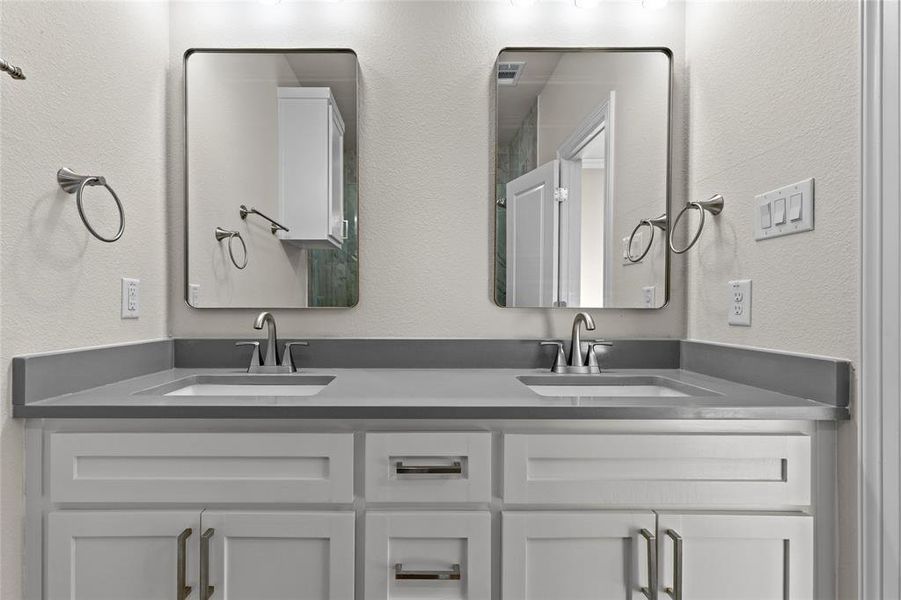 Bathroom with a textured wall and double vanity