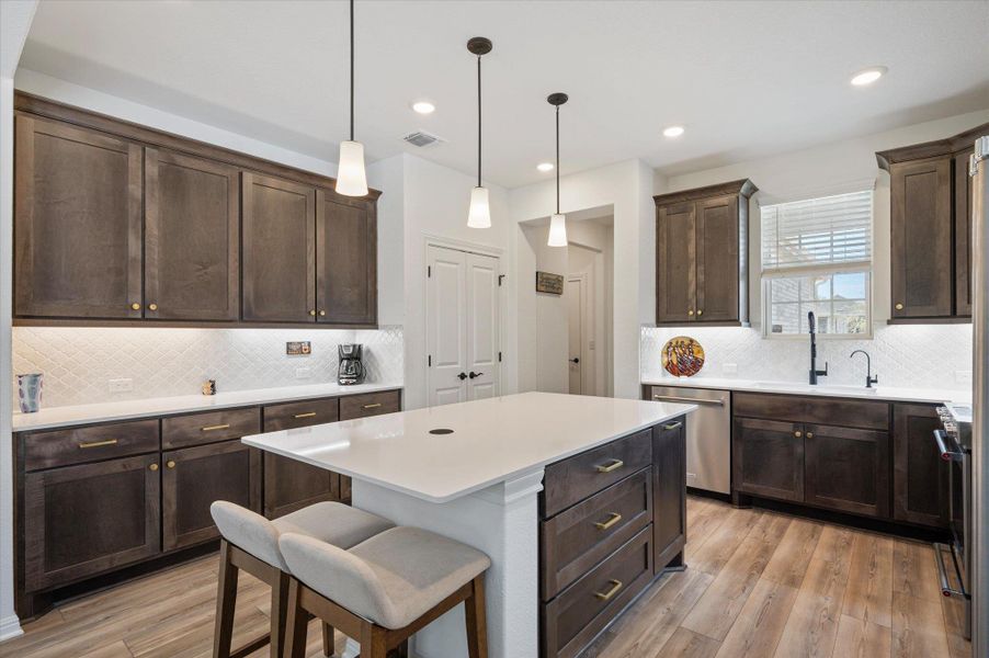Kitchen featuring light wood-style flooring, a center island, a kitchen breakfast bar, and dark wood finish cabinets Kitchen featuring light wood-style flooring, a center island, a kitchen breakfast bar, and dark wood finish cabinets