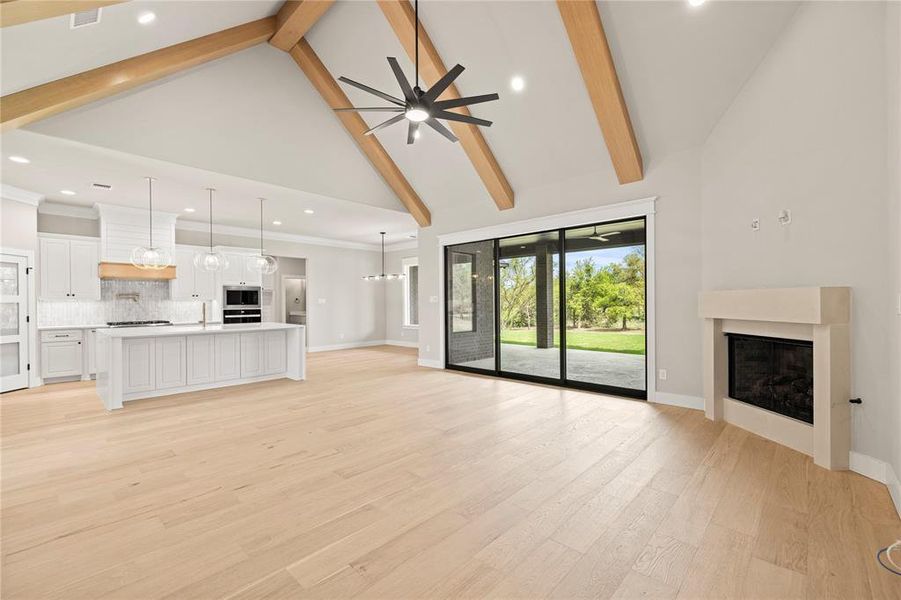 Unfurnished living room featuring high vaulted ceiling, a fireplace, beamed ceiling, recessed lighting, and light wood-style flooring Unfurnished living room featuring high vaulted ceiling, a fireplace, beamed ceiling, recessed lighting, and light wood-style flooring
