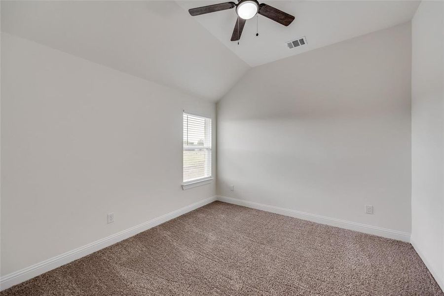 Carpeted empty room featuring lofted ceiling and ceiling fan