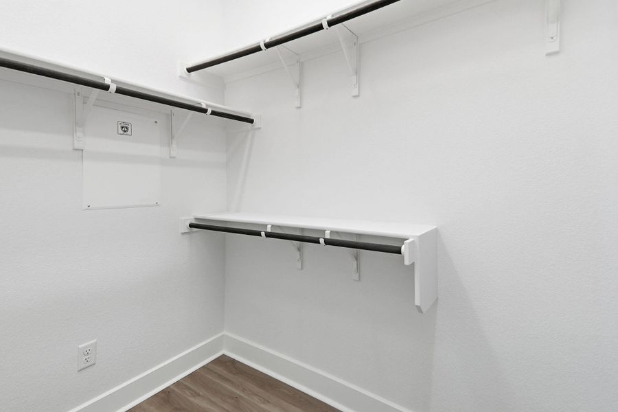 Walk in closet with dark wood-style floors