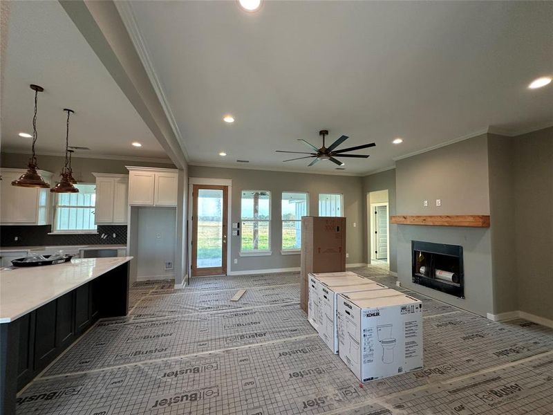 Kitchen with backsplash, crown molding, decorative light fixtures, white cabinets, and a kitchen island