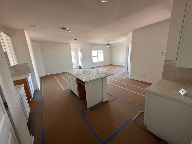 Kitchen featuring decorative backsplash, white cabinetry, a center island, and light stone counters Kitchen featuring decorative backsplash, white cabinetry, a center island, and light stone counters