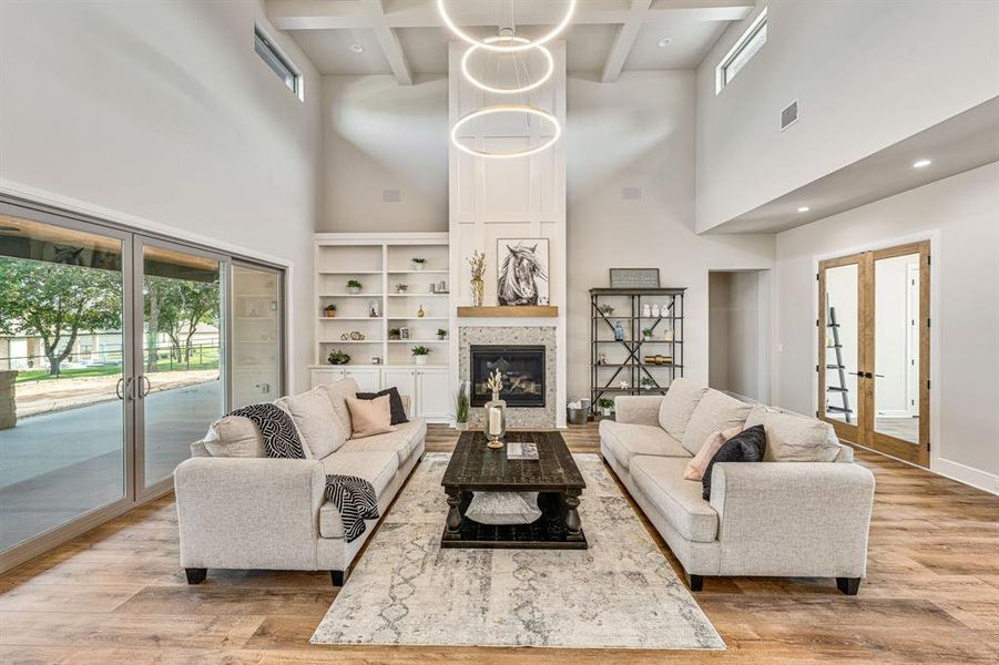 Living room featuring beamed ceiling, french doors, a towering ceiling, and light wood-type flooring