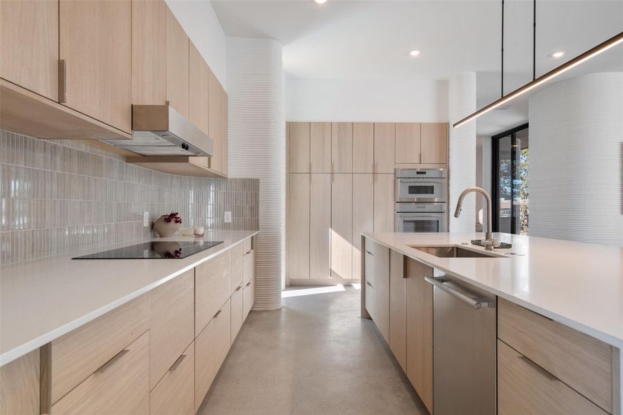 Kitchen with appliances with stainless steel finishes, light brown cabinetry, and sink