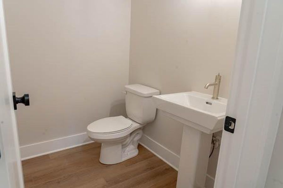 Bathroom featuring toilet, hardwood / wood-style floors, and sink Bathroom featuring toilet, hardwood / wood-style floors, and sink