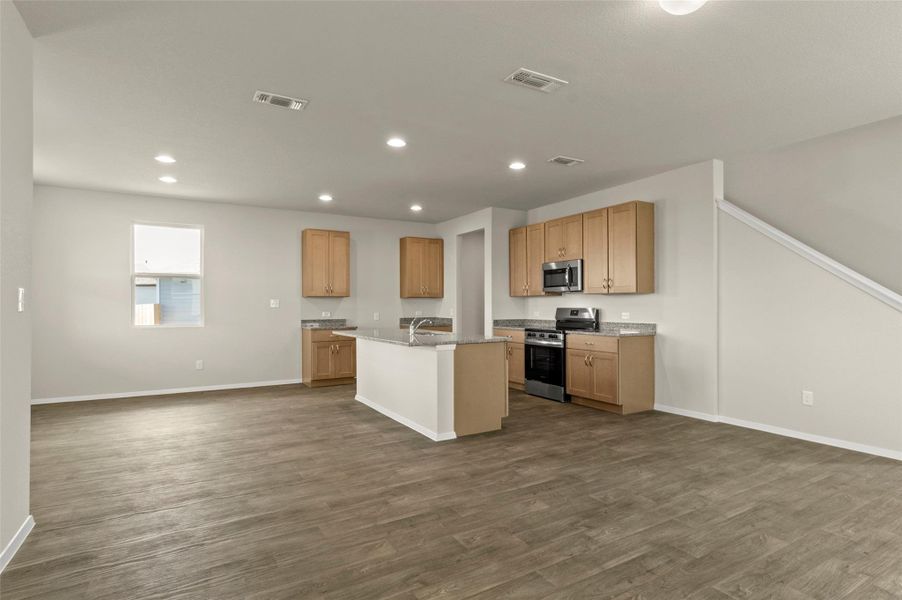 Kitchen featuring appliances with stainless steel finishes, dark wood finished floors, open floor plan, recessed lighting, and an island with sink