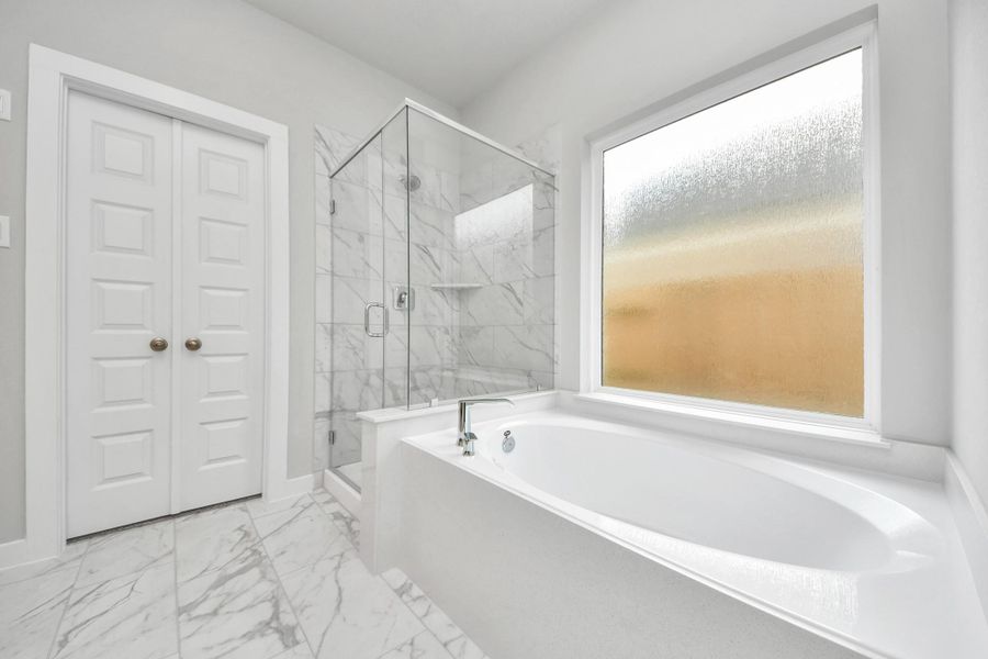 Indulge in a spa-like retreat within the confines of this primary bathroom. Delight in a spacious walk-in shower enveloped in stylish tile surround, unwind in a separate garden tub adorned with custom detailing.