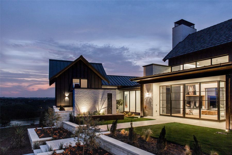 Back of property featuring board and batten siding, a standing seam roof, a metal roof, a chimney, and a lawn