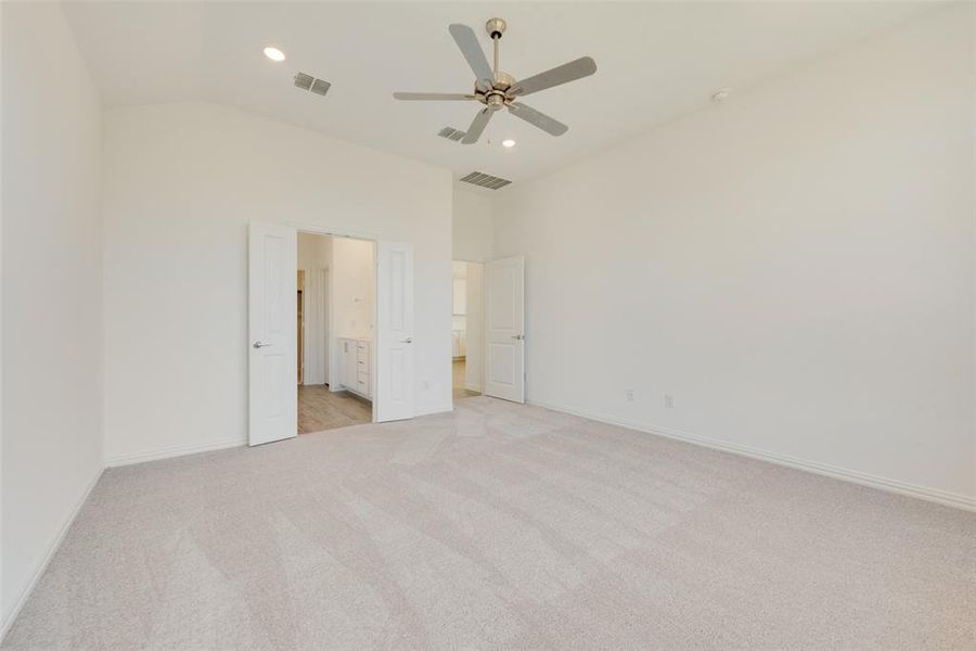 Unfurnished bedroom with ceiling fan, vaulted ceiling, and light colored carpet