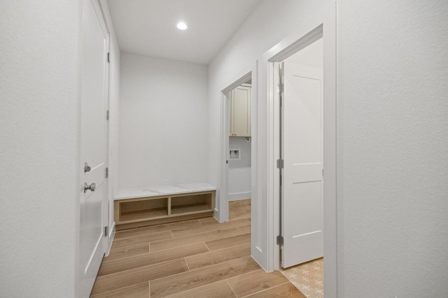 A streamlined mudroom featuring built-in storage bench and light-toned flooring, offering practicality and style.