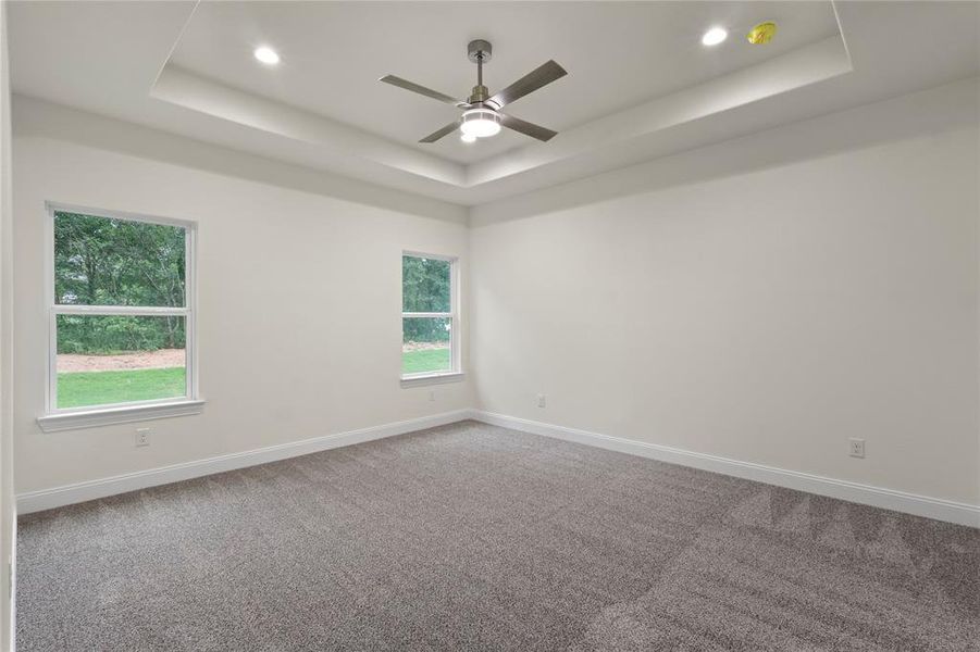 Spacious room featuring a tray ceiling, recessed lighting, and a contemporary ceiling fan Spacious room featuring a tray ceiling, recessed lighting, and a contemporary ceiling fan