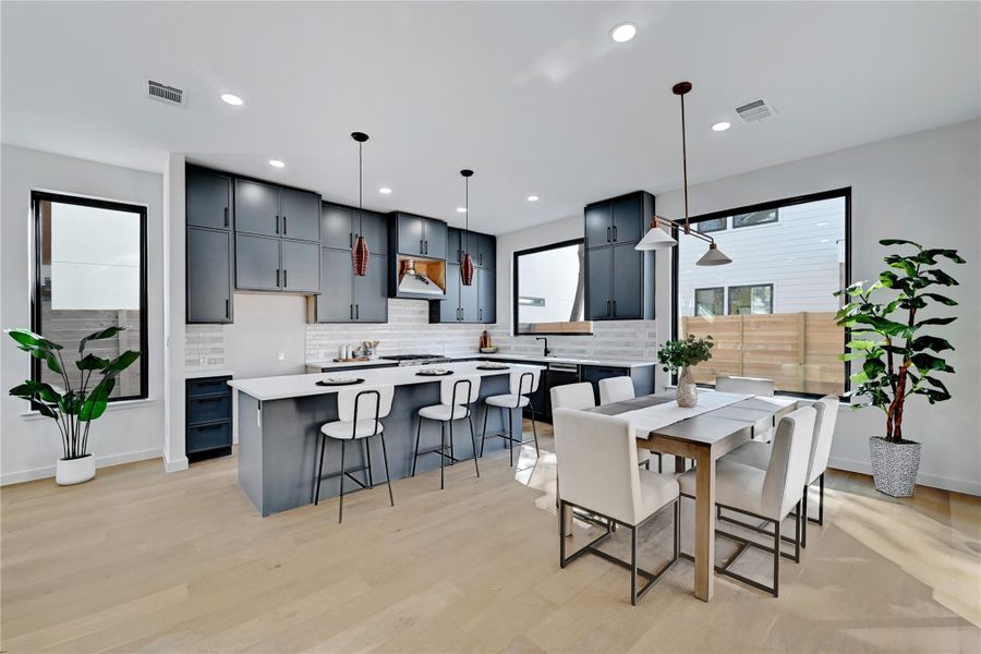 Kitchen with decorative light fixtures, a center island, light hardwood / wood-style flooring, and tasteful backsplash