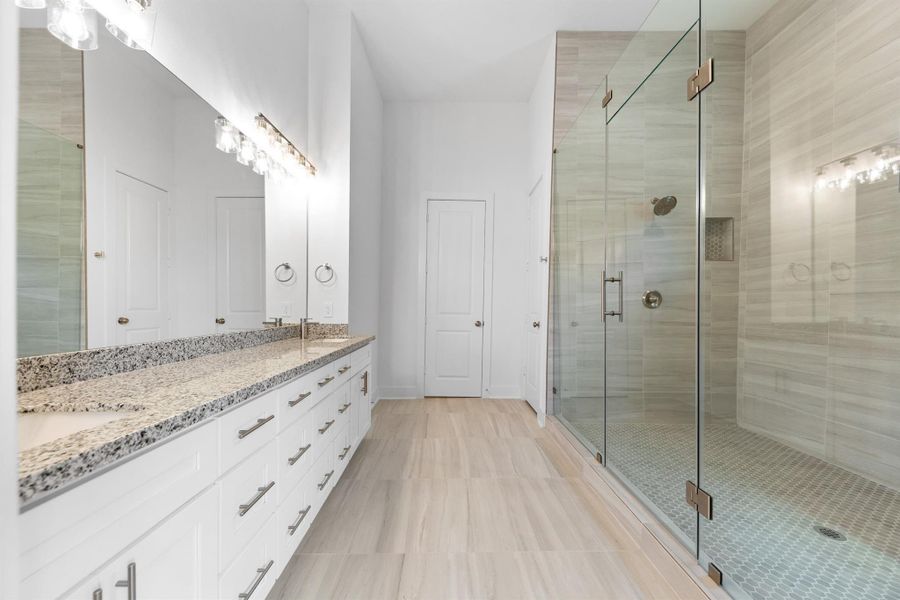 Primary bath features an extra-long vanity with dual sinks, providing ample space and convenience.