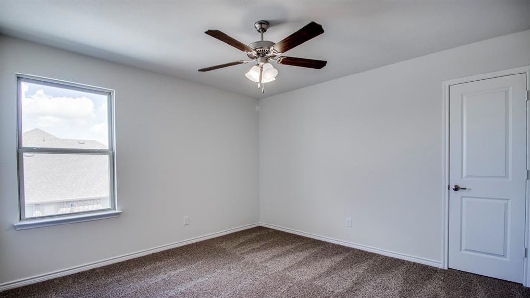 Unfurnished room with dark colored carpet and ceiling fan Unfurnished room with dark colored carpet and ceiling fan