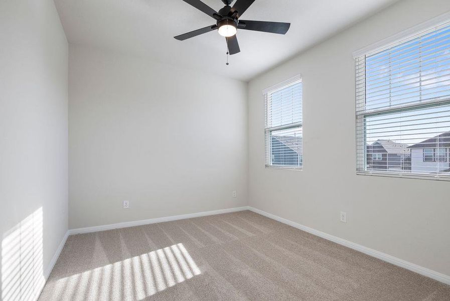 Carpeted spare room with baseboards and a ceiling fan