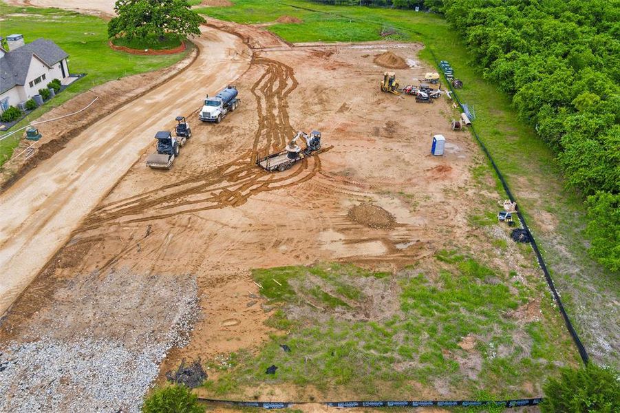 Expansive undeveloped lot featuring a partially cleared area, natural green space, and visible construction road access Expansive undeveloped lot featuring a partially cleared area, natural green space, and visible construction road access