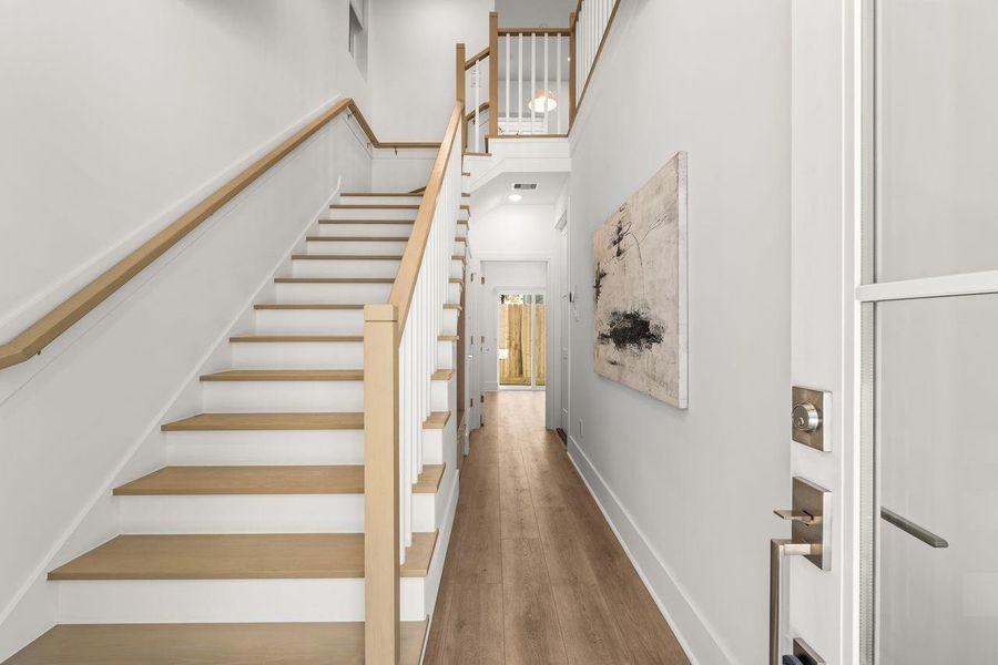 A bright, airy entryway with elevated ceilings and warm finishes creates an immediate sense of space and openness.