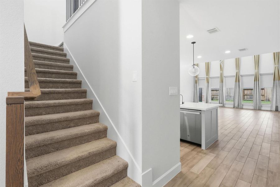 Ascend the plush carpeted staircase with rich wood railings and elegant wrought-iron spindles to discover the spacious second level, where additional living space and private bedrooms await.