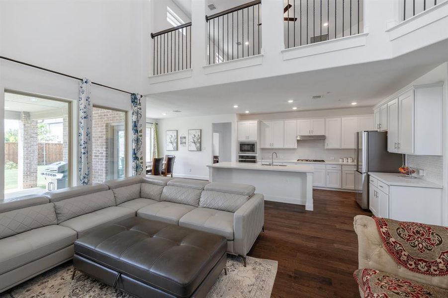 Living area featuring dark wood-style floors, a high ceiling, baseboards, and recessed lighting