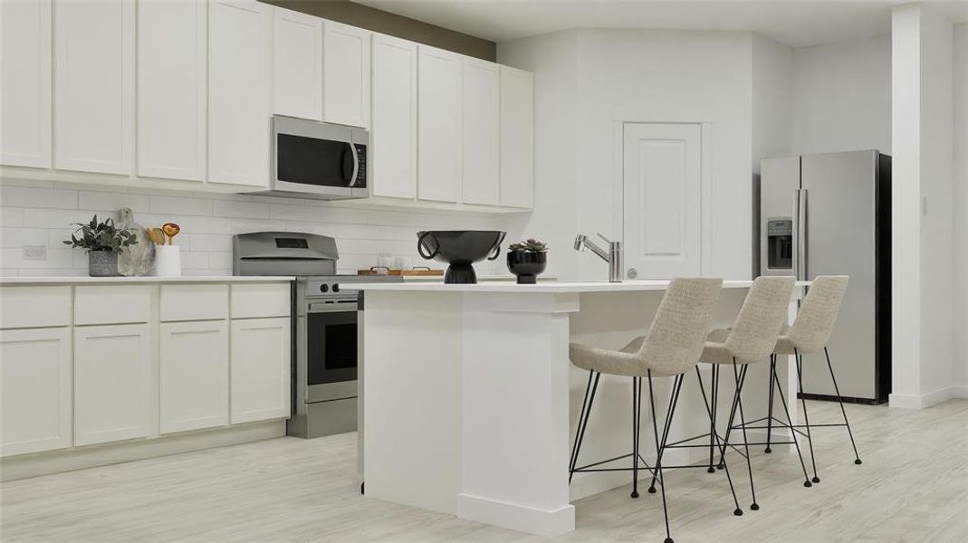 Kitchen featuring a center island with sink, stainless steel appliances, a breakfast bar area, white cabinetry, and tasteful backsplash