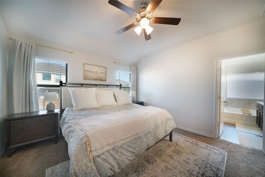 Carpeted bedroom with vaulted ceiling and a ceiling fan