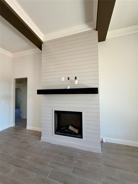 Detailed view of crown molding, a fireplace, wood finish floors, and beamed ceiling Detailed view of crown molding, a fireplace, wood finish floors, and beamed ceiling