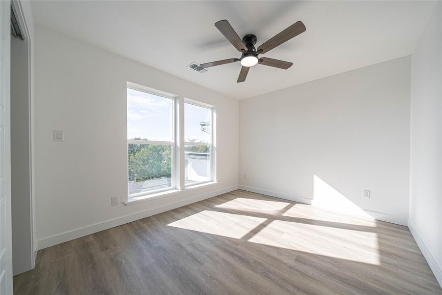 Empty room with wood finished floors and a ceiling fan