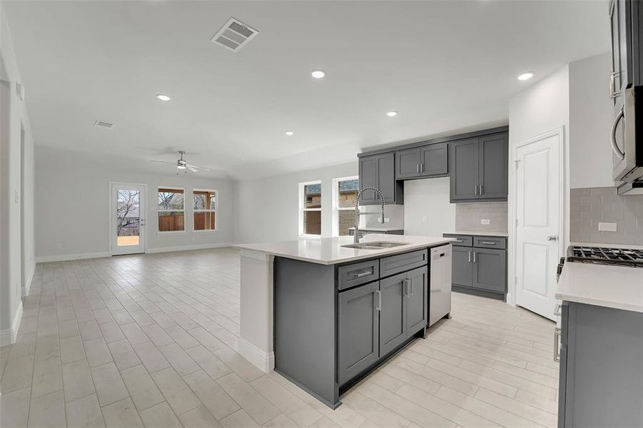 Kitchen featuring tasteful backsplash, a sink, visible vents, and gray cabinetry Kitchen featuring tasteful backsplash, a sink, visible vents, and gray cabinetry