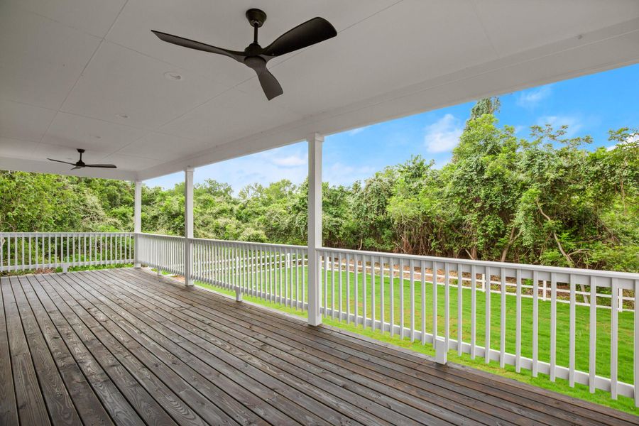 Wooden terrace featuring ceiling fan, a yard, and view of wooded area