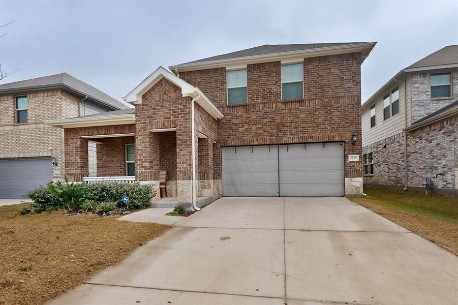 Traditional-style home with covered porch, brick siding, concrete driveway, and a garage Traditional-style home with covered porch, brick siding, concrete driveway, and a garage