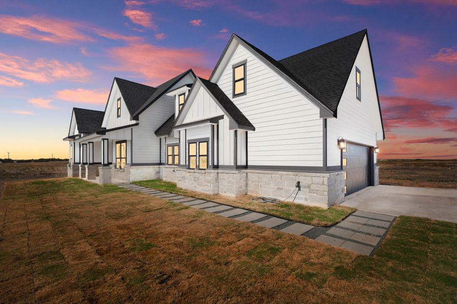 Dramatic gables and pristine white siding define this modern home against a vibrant sunset sky. Dramatic gables and pristine white siding define this modern home against a vibrant sunset sky.