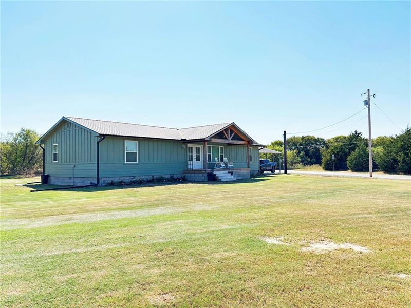 View of front of home featuring a porch, a front lawn, crawl space, and a metal roof View of front of home featuring a porch, a front lawn, crawl space, and a metal roof