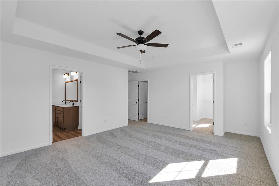 This spacious primary bedroom features soft carpet