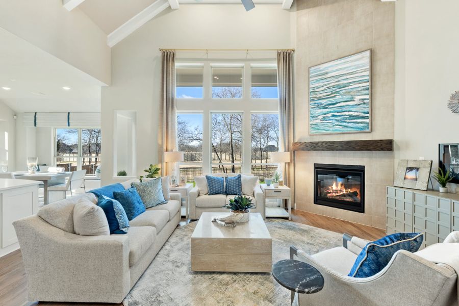 Living room with vaulted ceiling, gas fireplace, large windows, and neutral sofas with blue accent pillows Living room with vaulted ceiling, gas fireplace, large windows, and neutral sofas with blue accent pillows