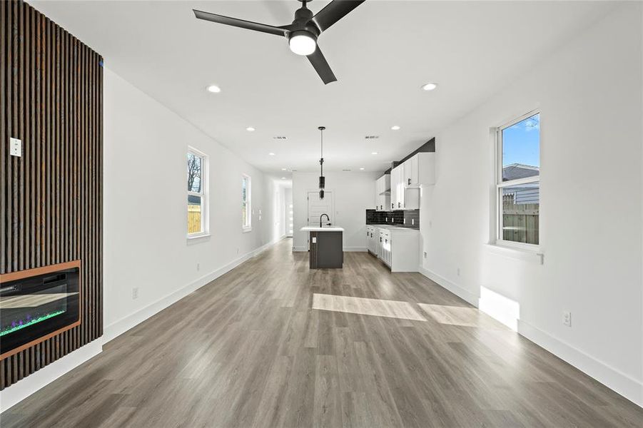 Unfurnished living room featuring ceiling fan, light wood-style flooring, recessed lighting, a sink, and baseboards