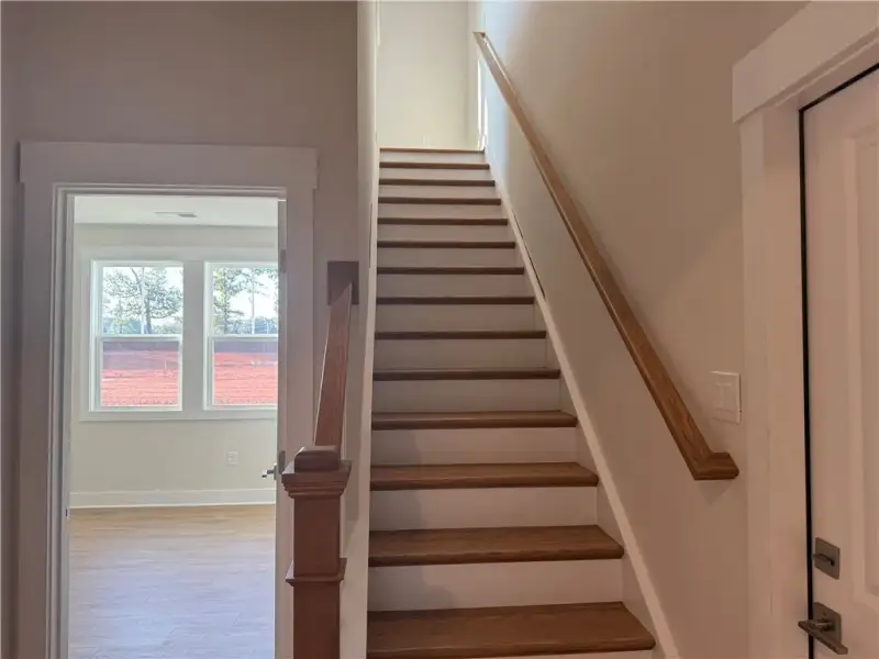 A classic wooden staircase ascends beside a bright