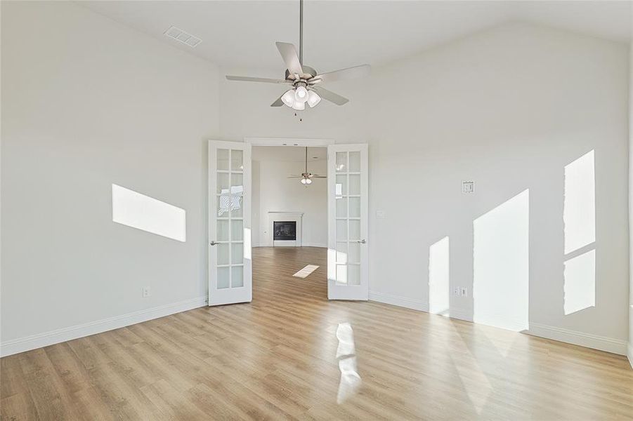 Unfurnished living room with french doors, ceiling fan, high vaulted ceiling, and light wood-type flooring