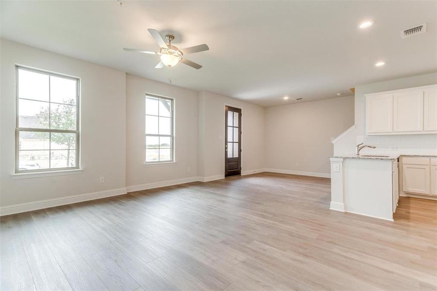 Unfurnished living room featuring ceiling fan, sink, and light wood-type flooring