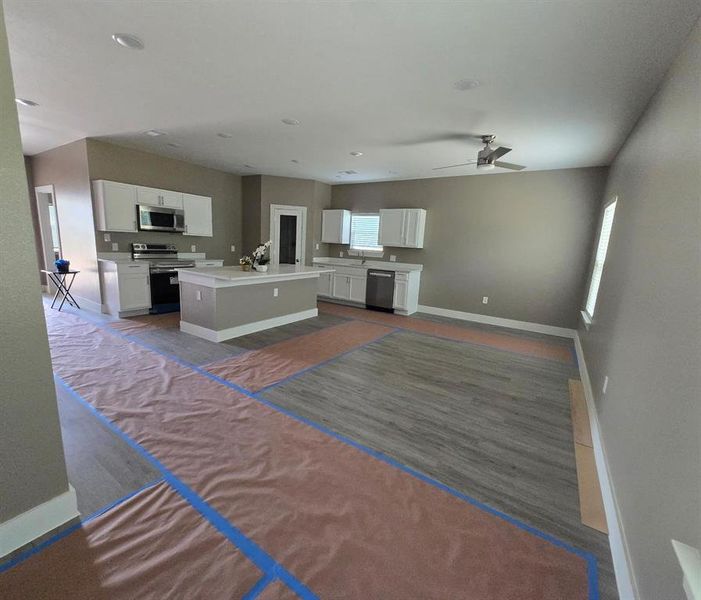 Kitchen featuring stainless steel appliances, white cabinetry, light countertops, open floor plan, and recessed lighting Kitchen featuring stainless steel appliances, white cabinetry, light countertops, open floor plan, and recessed lighting