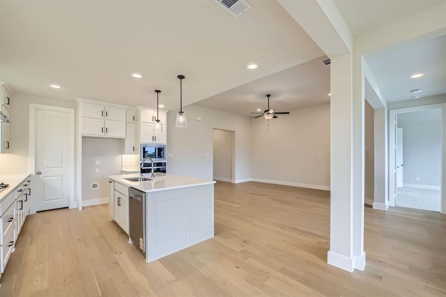 Kitchen featuring ceiling fan, stainless steel appliances, light wood-style flooring, white cabinetry, and light countertops