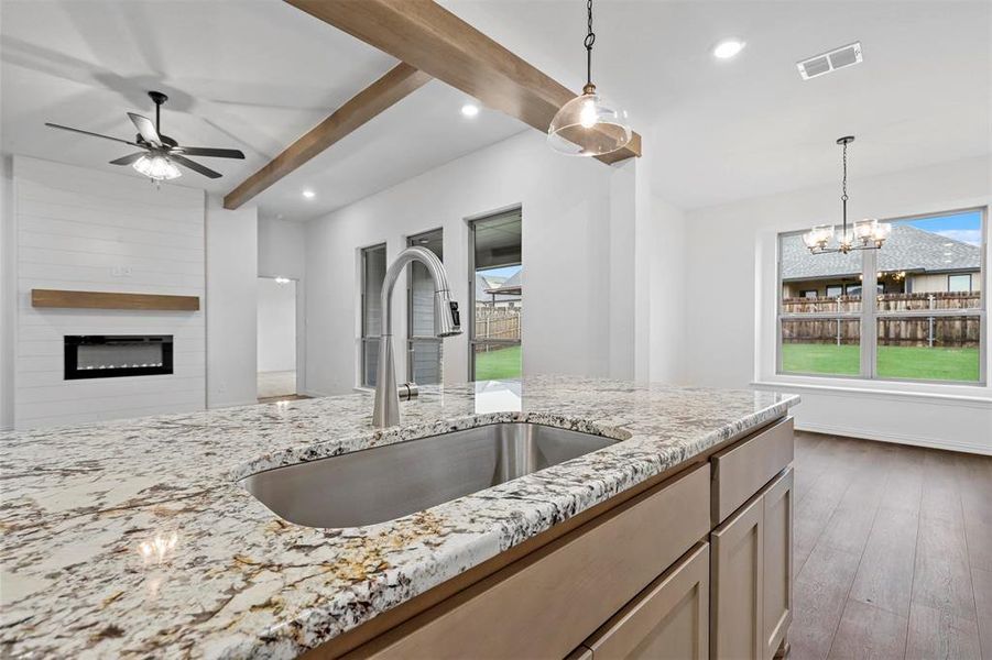 Kitchen featuring a large fireplace, wood-type flooring, sink, and beam ceiling