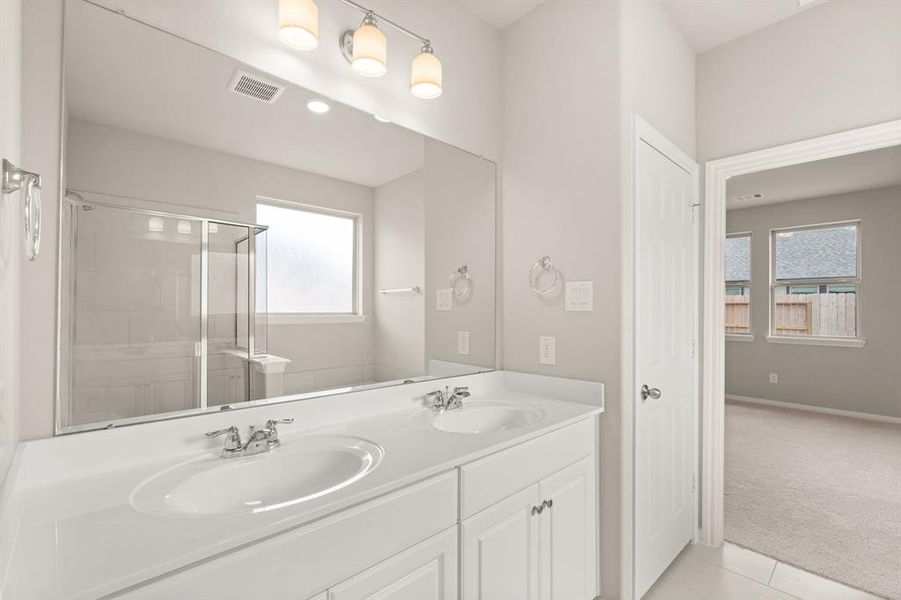 The en-suite bathroom offers a spa-like atmosphere with its elegant design, high end finishes, and tasteful lighting, creating a retreat within your own home.