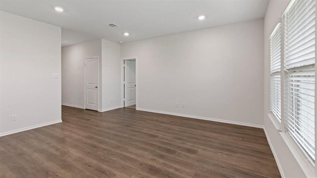Spacious room featuring wood-finish flooring, recessed lighting, and white walls