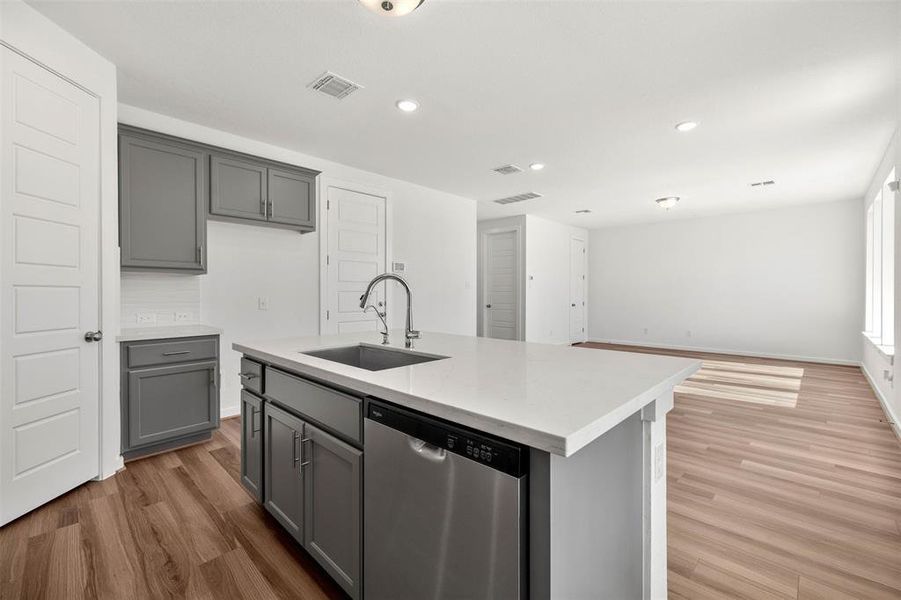 Kitchen with stainless steel dishwasher, an island with sink, gray cabinets, dark wood-style flooring, and recessed lighting Kitchen with stainless steel dishwasher, an island with sink, gray cabinets, dark wood-style flooring, and recessed lighting