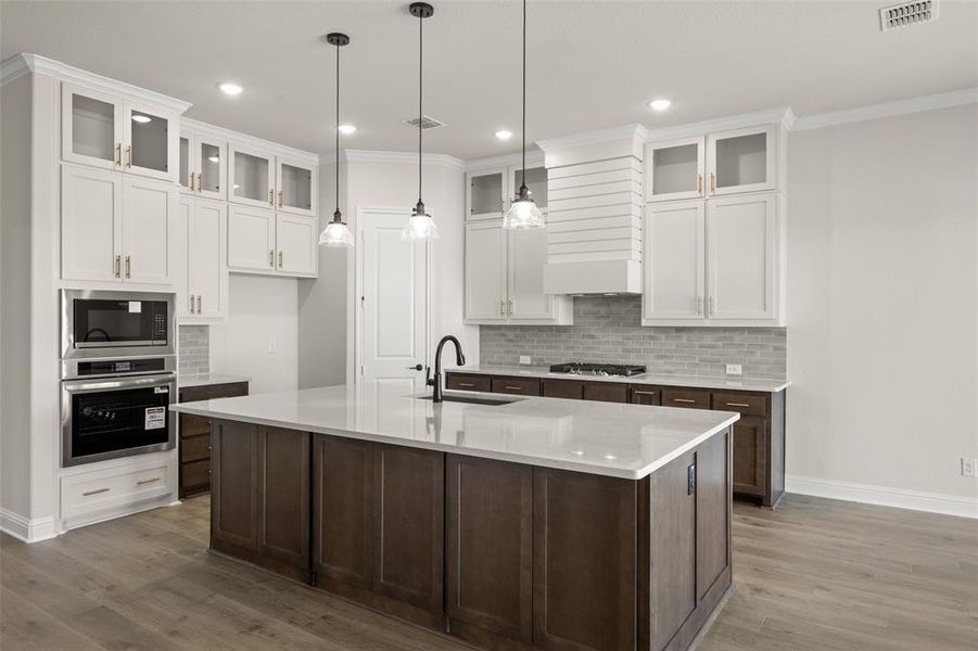 Kitchen with large island with quartz countertops, decorative lighting, and a pantry.
