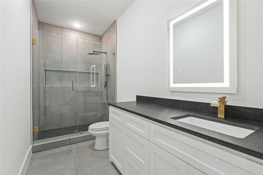 Full bath featuring vanity, a shower stall, and light tile patterned floors Full bath featuring vanity, a shower stall, and light tile patterned floors
